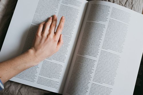 Free From above of crop anonymous female searching for information in article of book Stock Photo