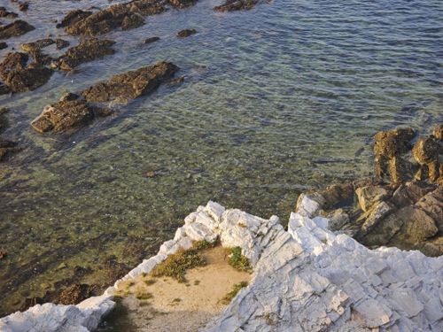 Free Clear coastal waters and rocky shore at Rizhao, China, with sunlit textures and serene ambiance. Stock Photo