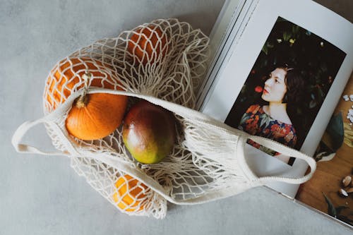 Free Top view of opened recipe book at table together with handbag with assorted fruits inside Stock Photo