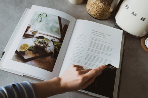 Free Anonymous housewife paging cookbook in kitchen Stock Photo