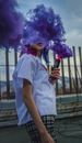 Unrecognizable woman with colored smoke bomb creating cloud effect outdoors