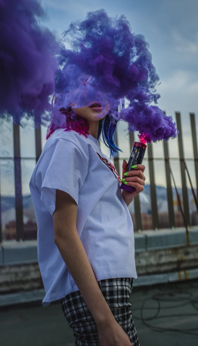 Unrecognizable Woman With Colored Smoke Bomb Creating Cloud Effect Outdoors