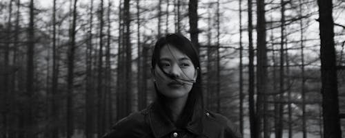 Contemplative Asian woman standing in forest