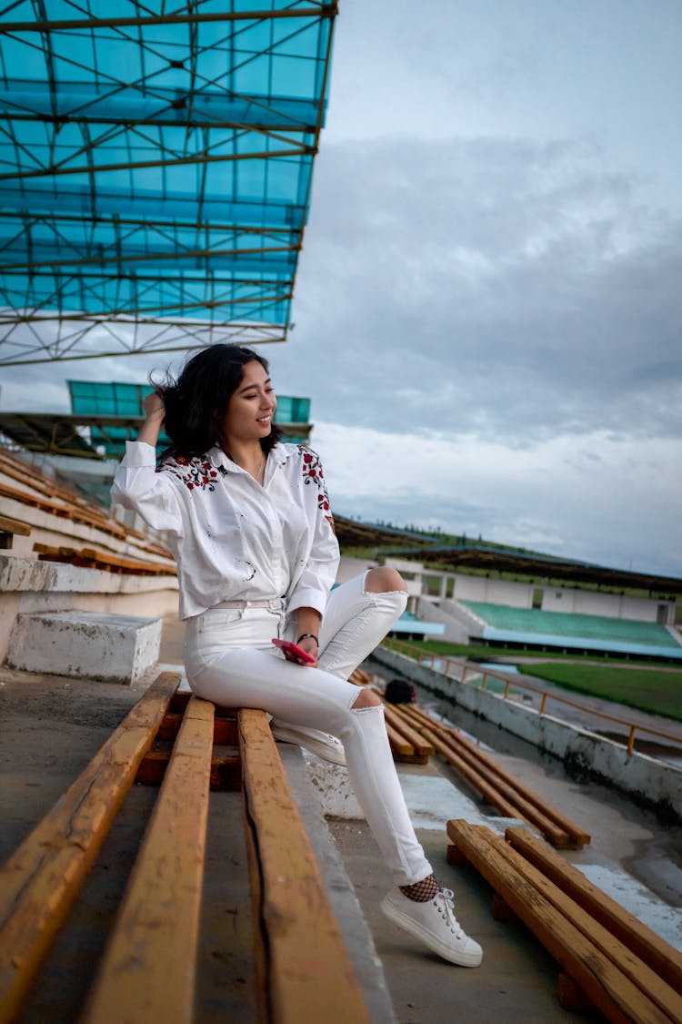 Slim Elegant Asian Model Sitting On Bench In Football Stadium