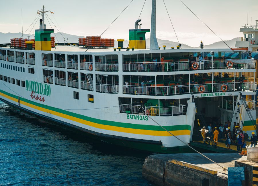 A bustling ferry docking at Batangas port with passengers disembarking.