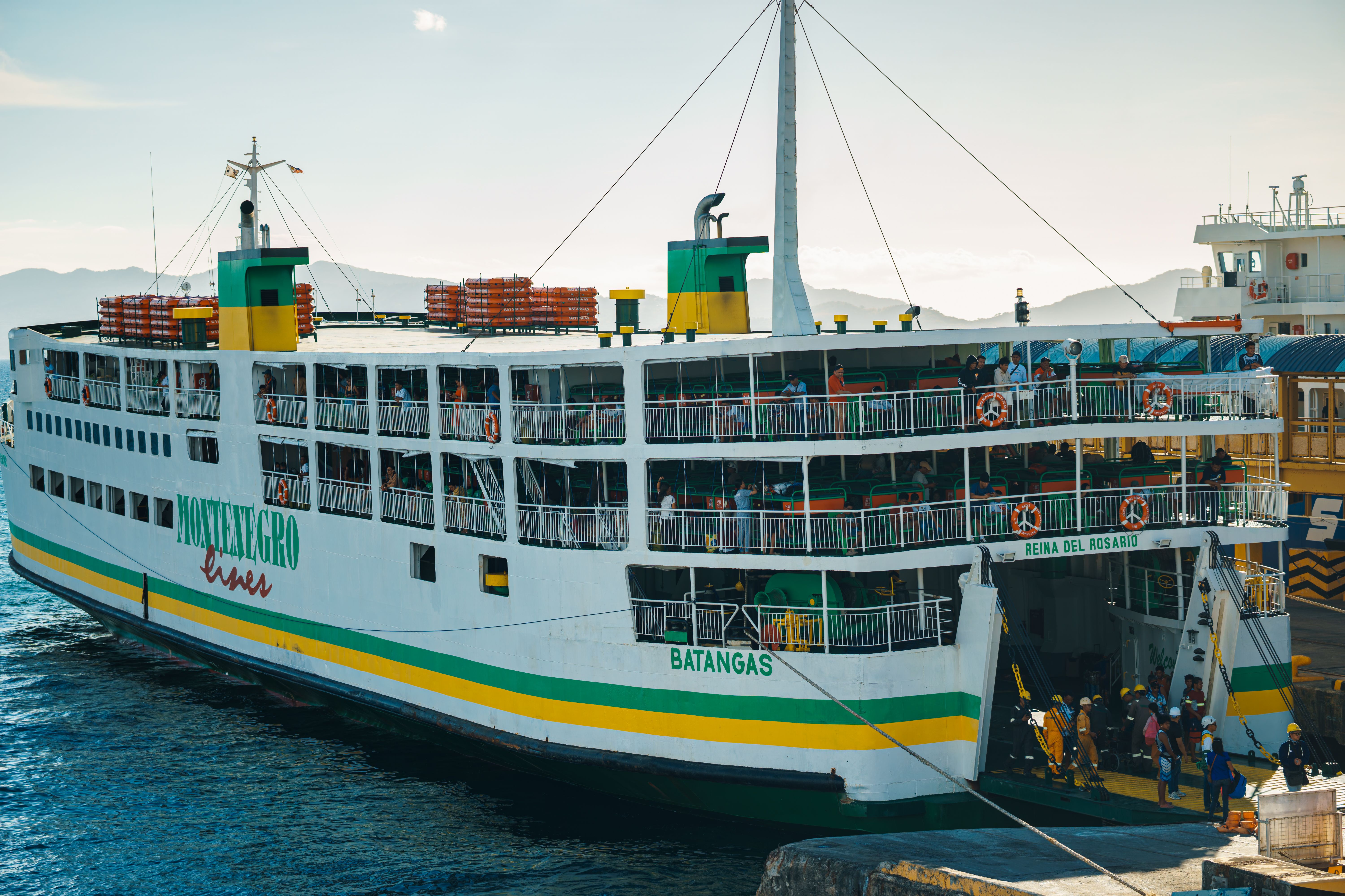 Montenegro Lines ferry at Batangas port with passengers embarking in a coastal setting.