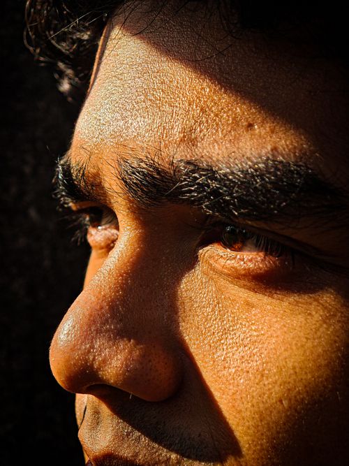 Free Detailed closeup of a man's face highlighted by warm sunlight in Indonesia. Stock Photo