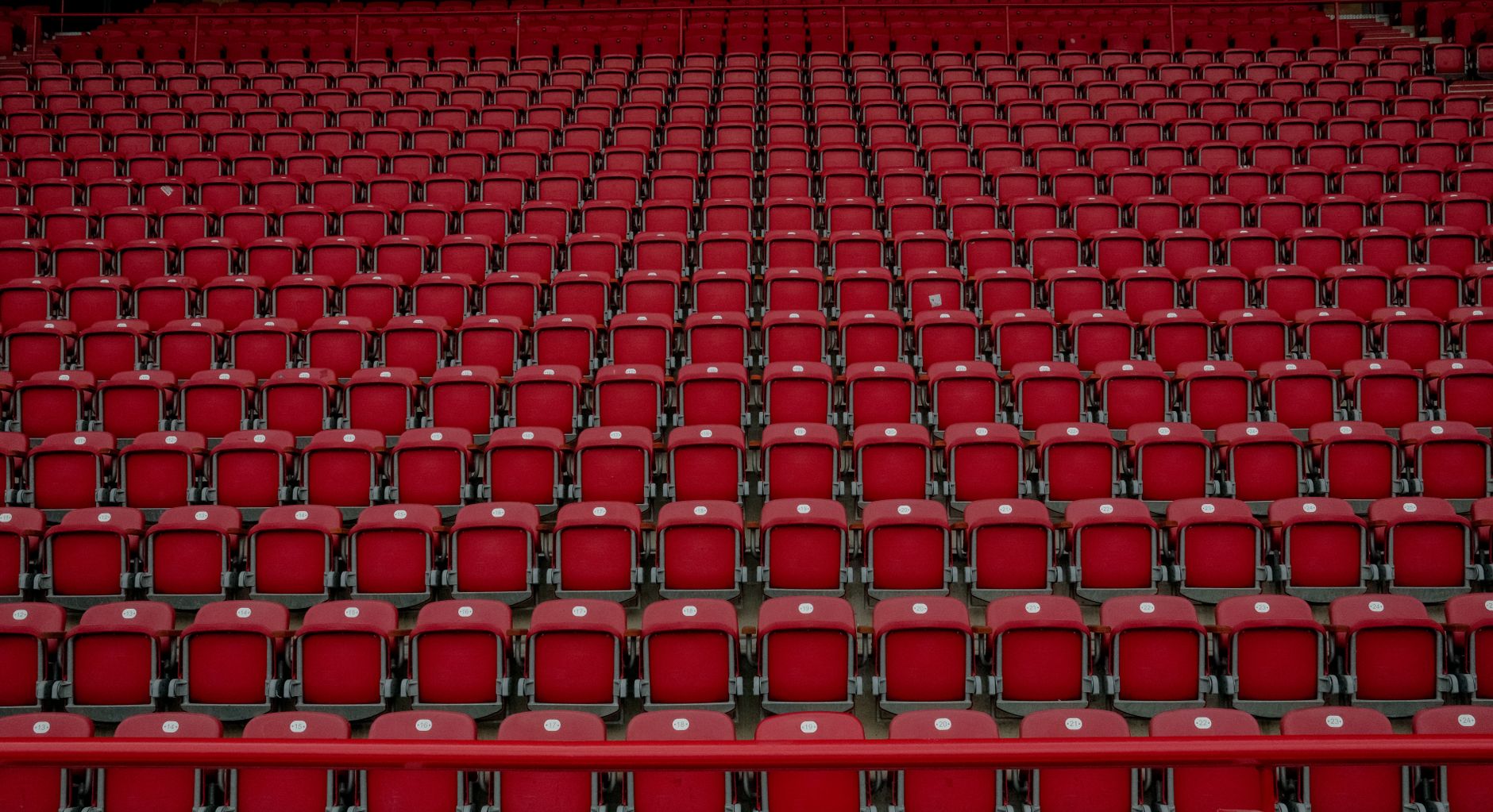 Empty football stadium seating surrounding a meticulously marked pitch during a quiet tournament rest day