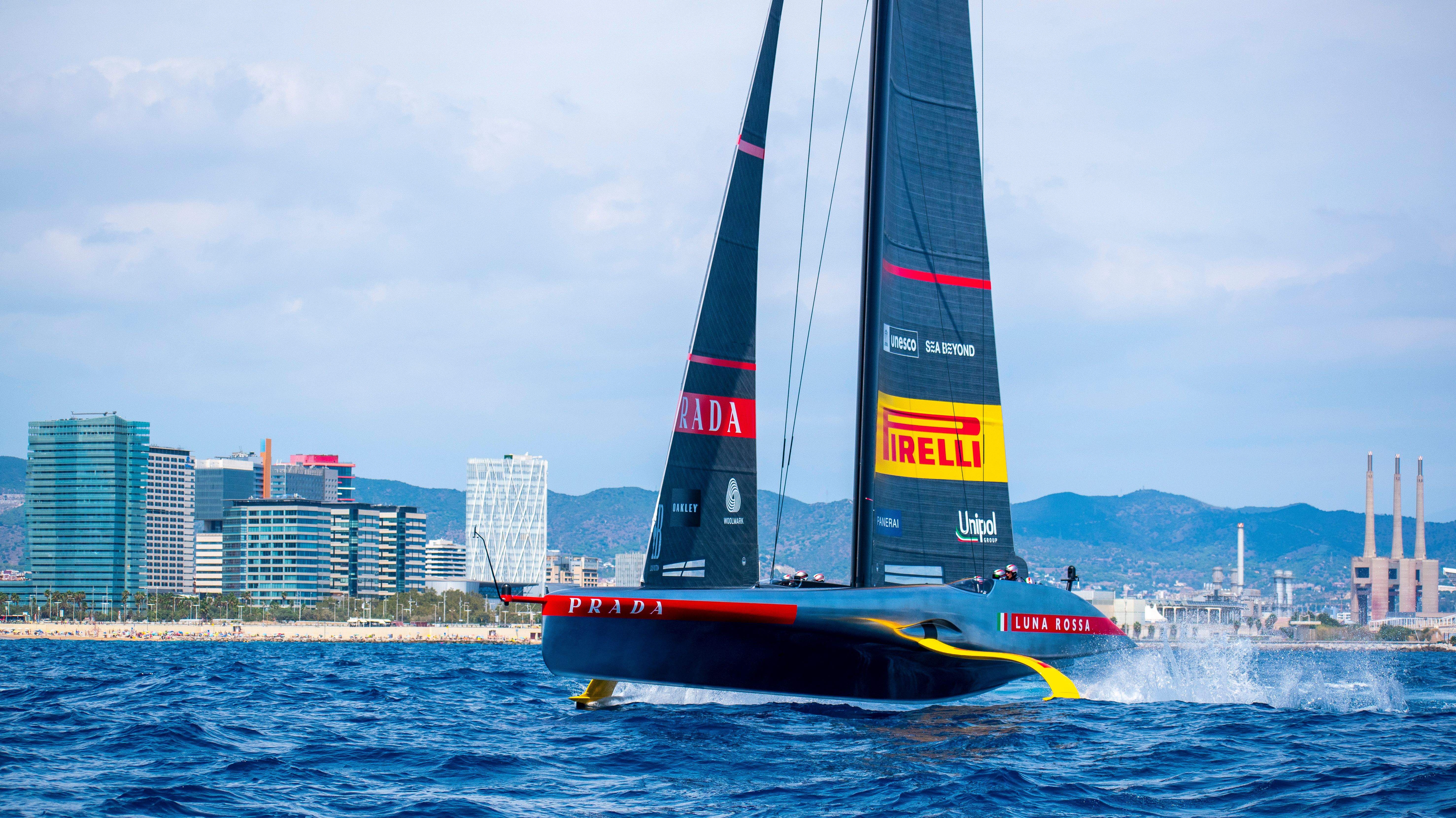 Spectacular Sunset Sailing Yacht Experience Small Group Review: Gran Canaria's Golden Hour Magic Review 2026 - A sleek sailing yacht glides past the Barcelona city skyline under a vibrant blue sky.