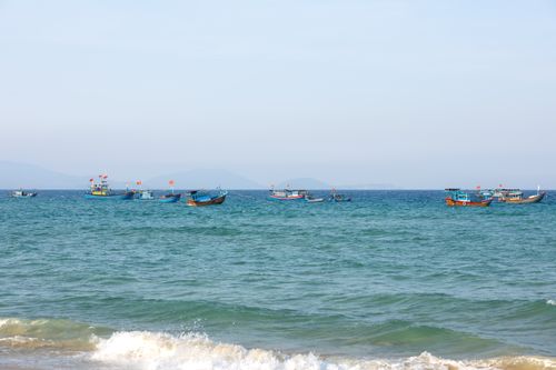 Free Fishing boats with flags floating on the calm sea under a clear sky showcasing maritime beauty. Stock Photo