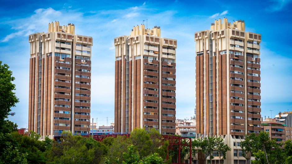 Tres modernos edificios residenciales de gran altura se alzan contra un cielo azul claro, mostrando arquitectura urbana.
