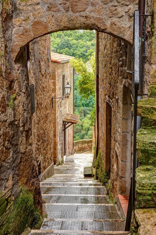 Free Explore the quaint medieval street in Pitigliano with its picturesque stone architecture and lush surroundings. Stock Photo