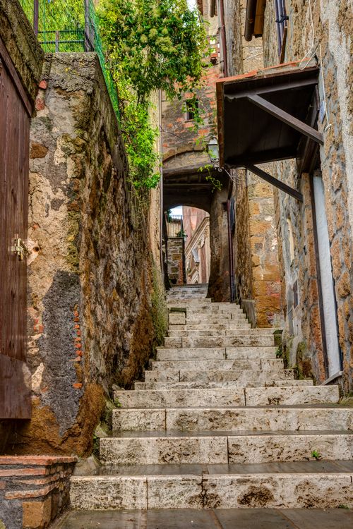 Free Explore a picturesque medieval alleyway with stone steps and ancient architecture in Tuscany. Stock Photo