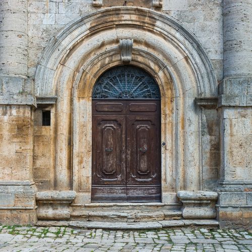 Free A vintage wooden door set in a stone archway typical of Tuscan architecture. Stock Photo
