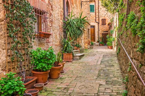 Free Picturesque brick alley with potted plants in a medieval Tuscan town. Stock Photo