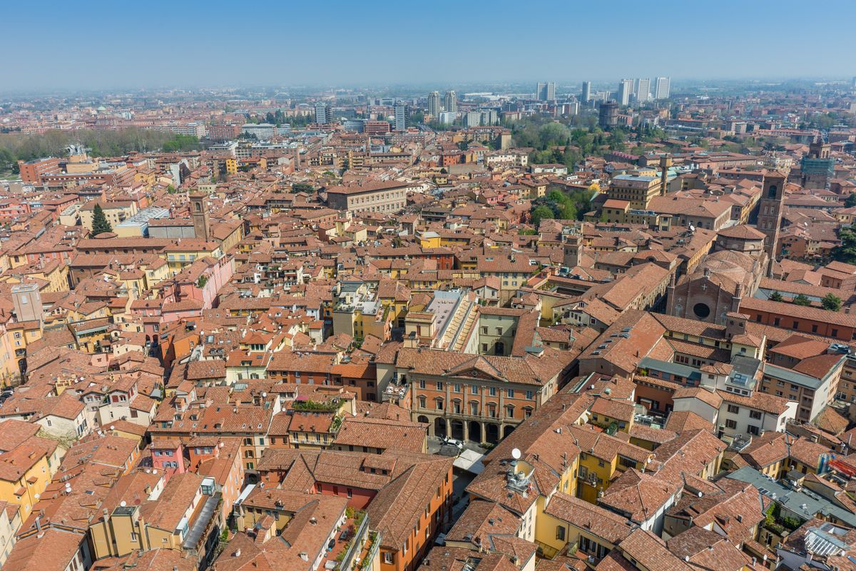 Bolognas Meer aus Terrakottadächern und mittelalterlichen Türmen von oben, mit den Hügeln dahinter