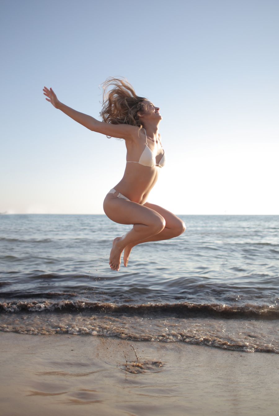 Woman jumping for joy on a sunny beach