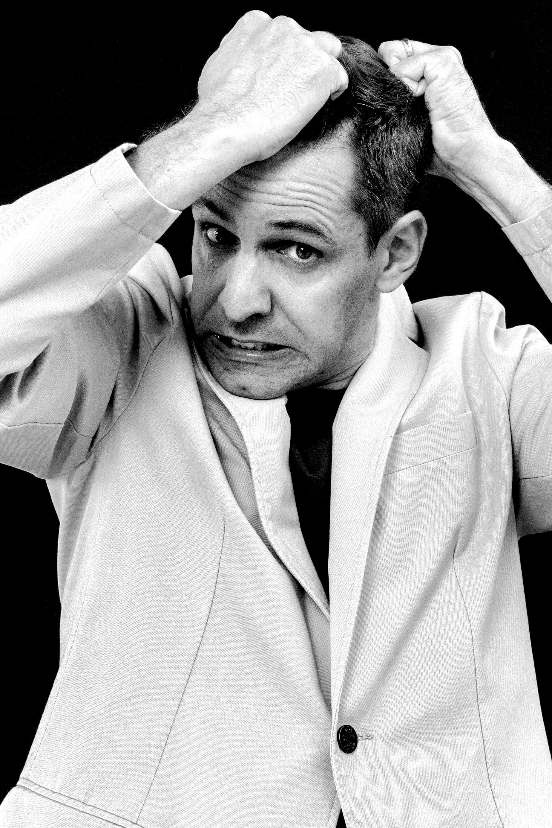 A grayscale portrait of an expressive man holding his head, conveying frustration or stress.