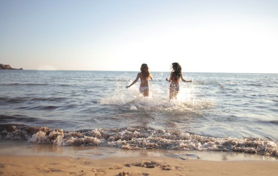 Two women enjoying a refreshing swim at a scenic beach on a sunny day.