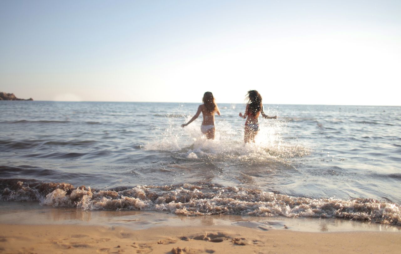 two women enjoying a refreshing swim at a scenic beach on a sunny day