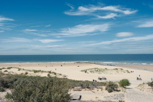 Free A serene beach scene with clear skies, sand dunes, and gentle ocean waves. Stock Photo