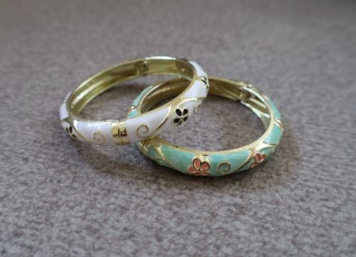 Free Stylish gold bracelets with intricate floral enamel design on a textured background. Stock Photo