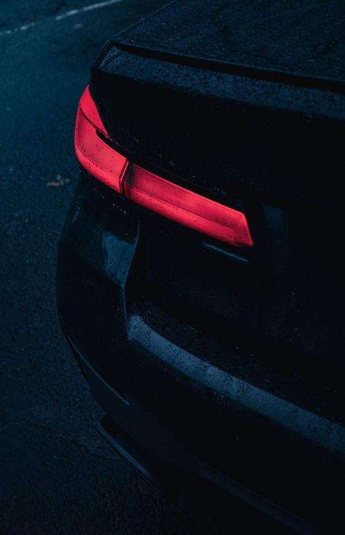 Free A close-up of a car's tail light illuminated in a dark, rainy setting. Stock Photo