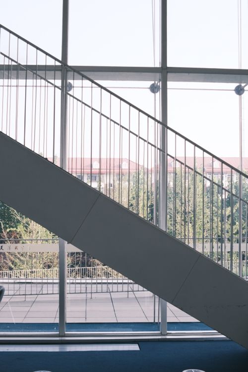 Free Modern staircase with geometric lines against a large window backdrop. Stock Photo