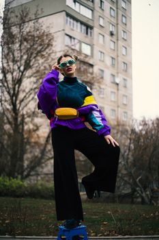 A woman showcasing vibrant retro fashion poses confidently outdoors with bold colors and urban vibes.