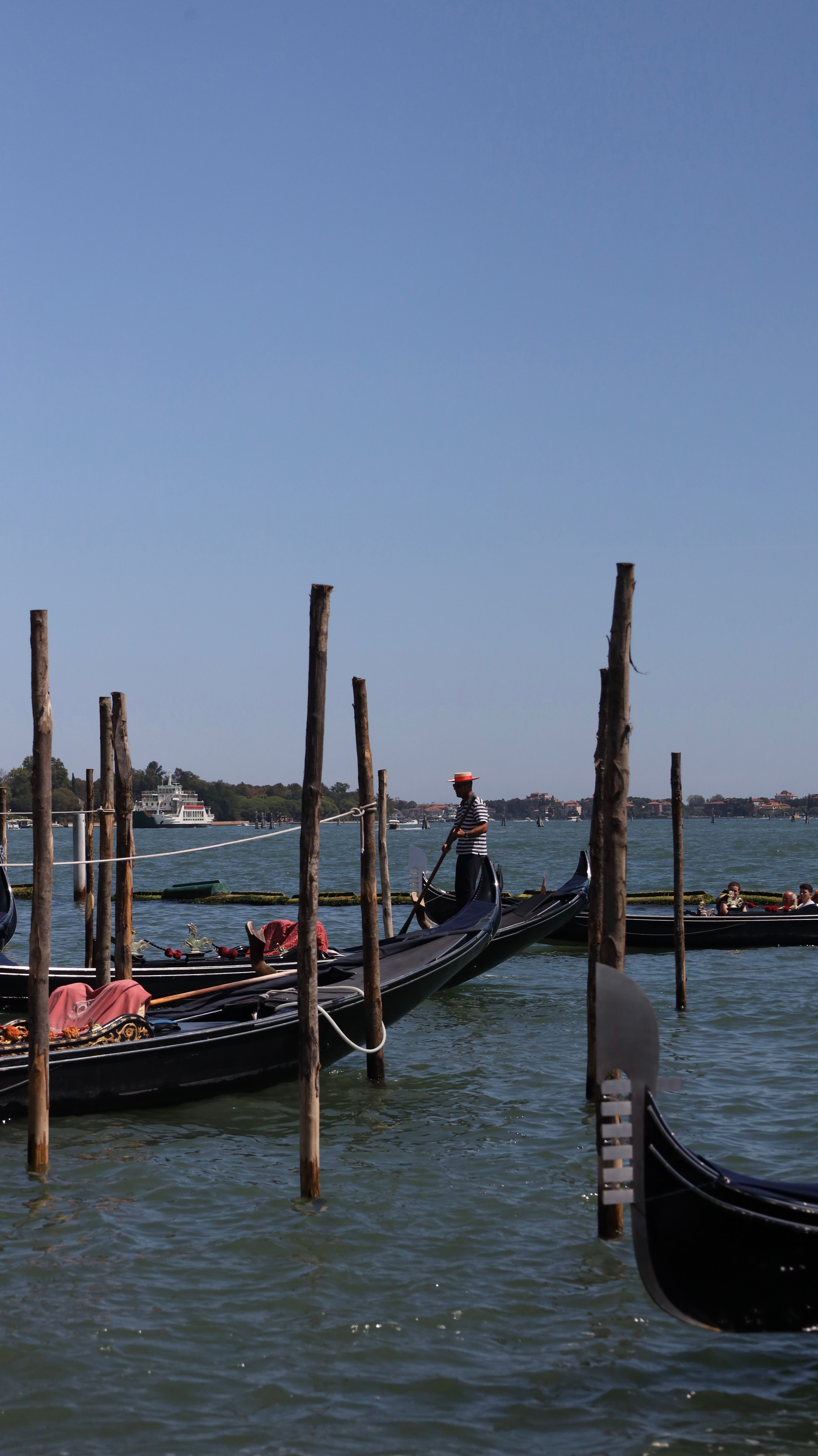 Gondolas moored in Venice under clear blue skies, showcasing classic Italian scenery.