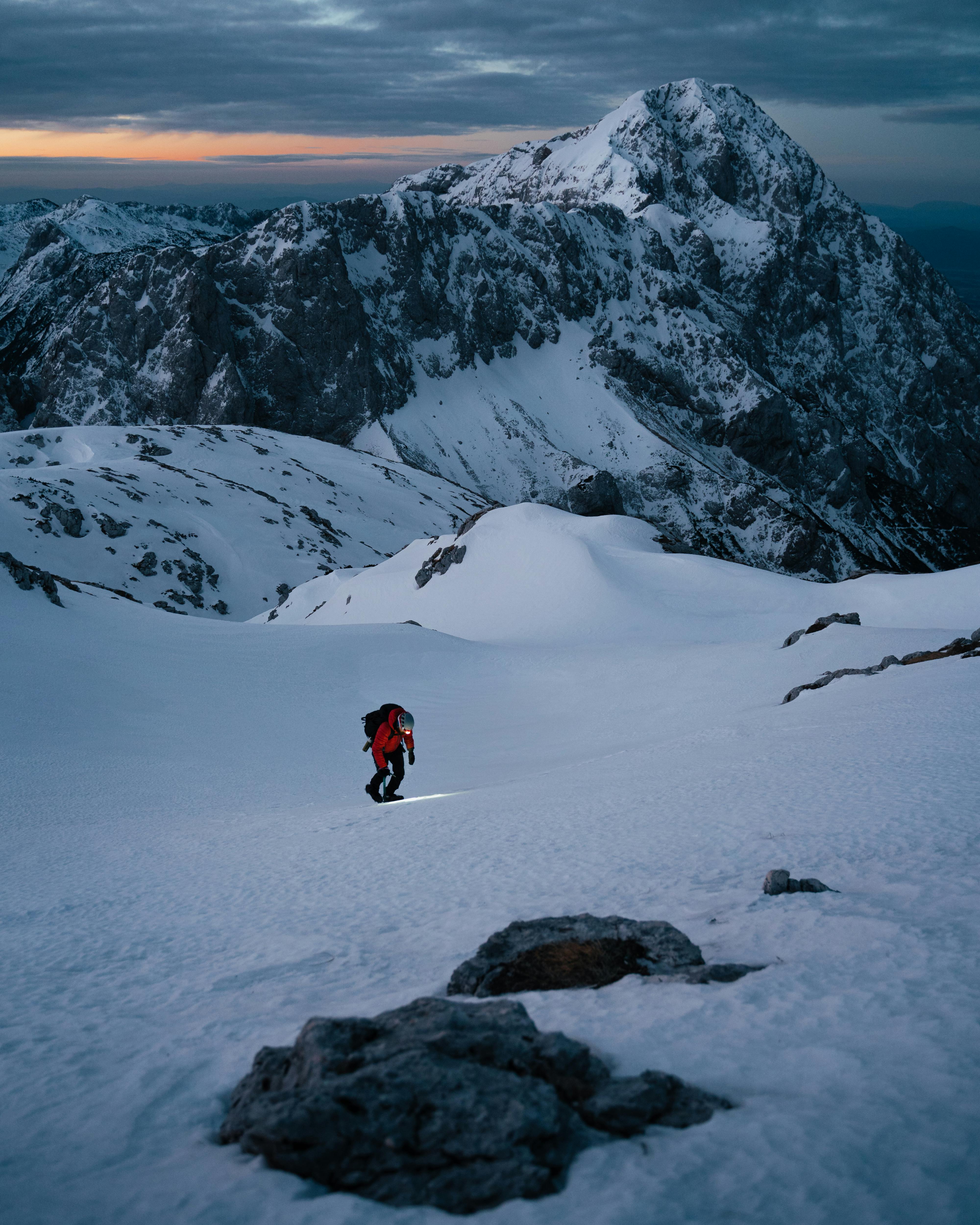 person in red jacket and black pants walking on snow covered ground