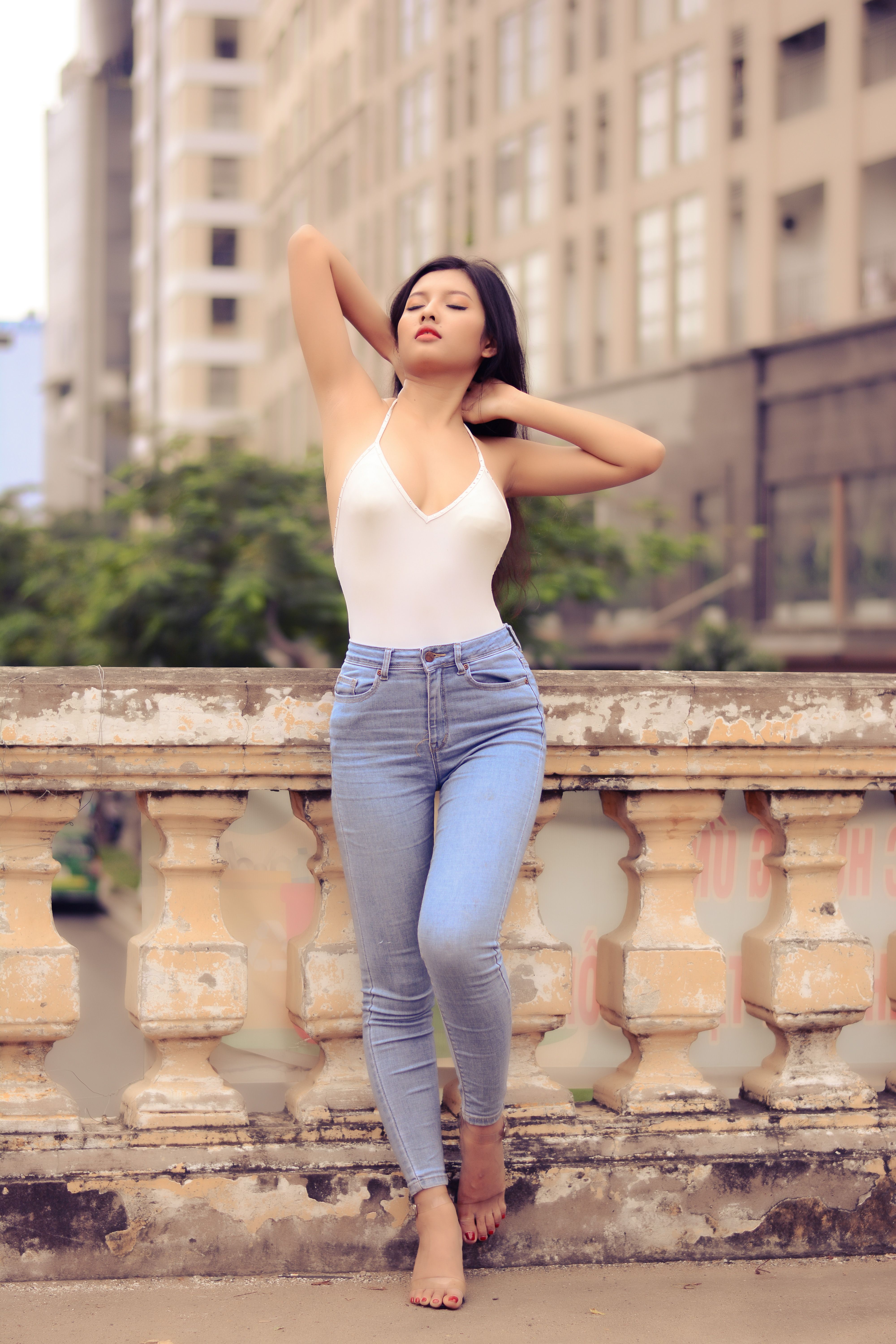 Stylish woman in casual jeans and top posing outdoors in an urban environment.