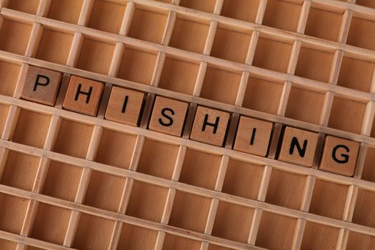 High-angle view of wooden letter tiles spelling 'Phishing', representing online security threats.