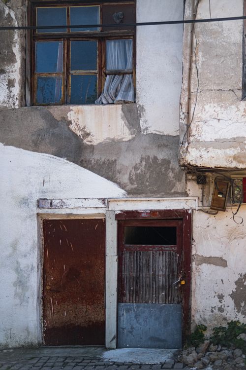 Free Weathered, rustic facade showcasing mismatched doors and window with peeling paint. Stock Photo