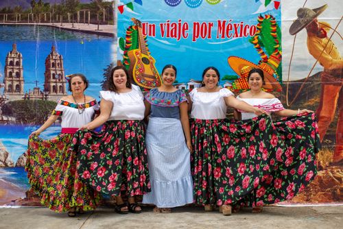 Free Five women in colorful traditional Mexican dresses at a cultural celebration with festive backdrop. Stock Photo
