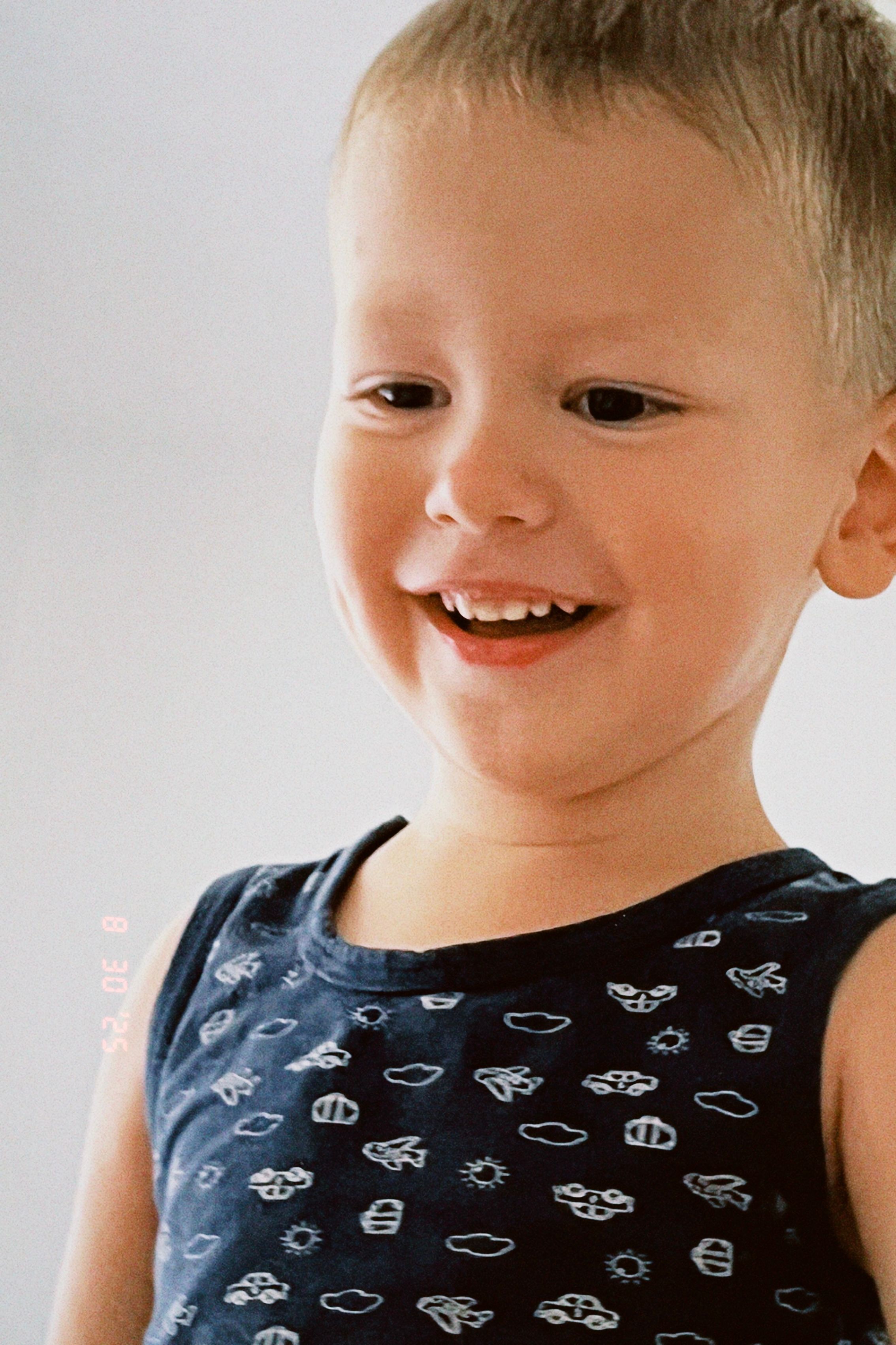 Joyful toddler smiling brightly indoors, captured in a candid moment.