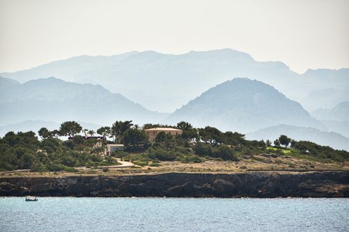 Free Serene coastal landscape with lush greenery and distant mountains. Stock Photo