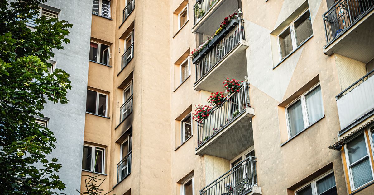 Exterior view of a residential building in Wrocław featuring balconies adorned with flowers.