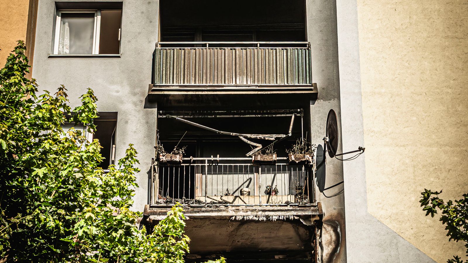 Façade d'immeuble d'habitation dont plusieurs balcons portent les traces noircies d'un incendie.