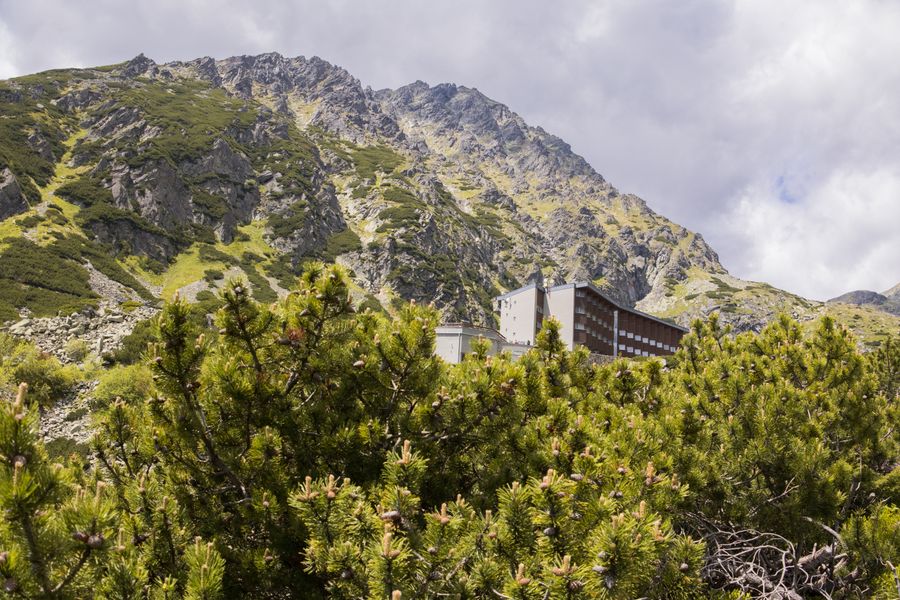 Horský hotel pod skalnatým svahem obrostlým kosodřevinou
