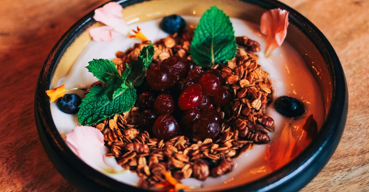 Greek yogurt bowl with coconut, almonds, and berries on a wooden table
