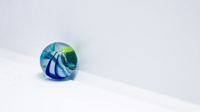 A single coloured glass marble on white — photo by Tuba Sen on Pexels