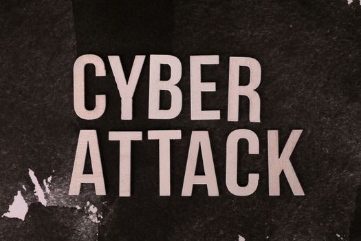 Text 'Cyber Attack' on textured dark paper highlights digital security threat concept.