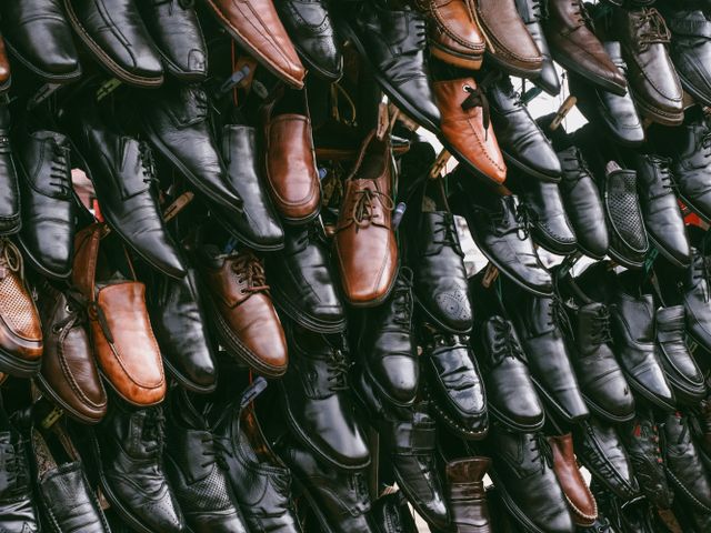 Assorted black and brown leather shoes arranged on a display wall