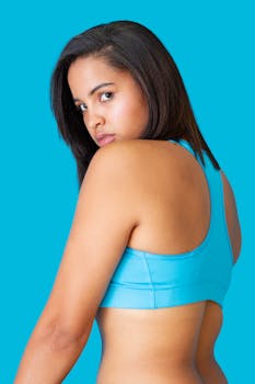 Confident woman looking over her shoulder wearing blue sportswear against a vibrant background.