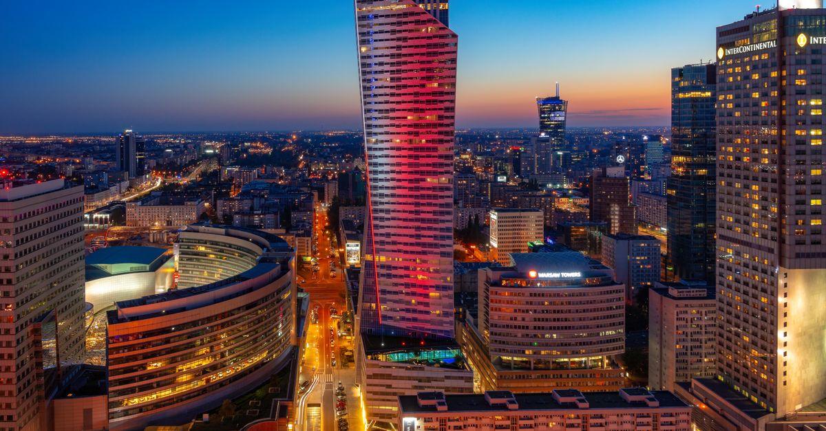 Aerial view of Warsaw's skyscrapers illuminated at twilight, showcasing vibrant city life.