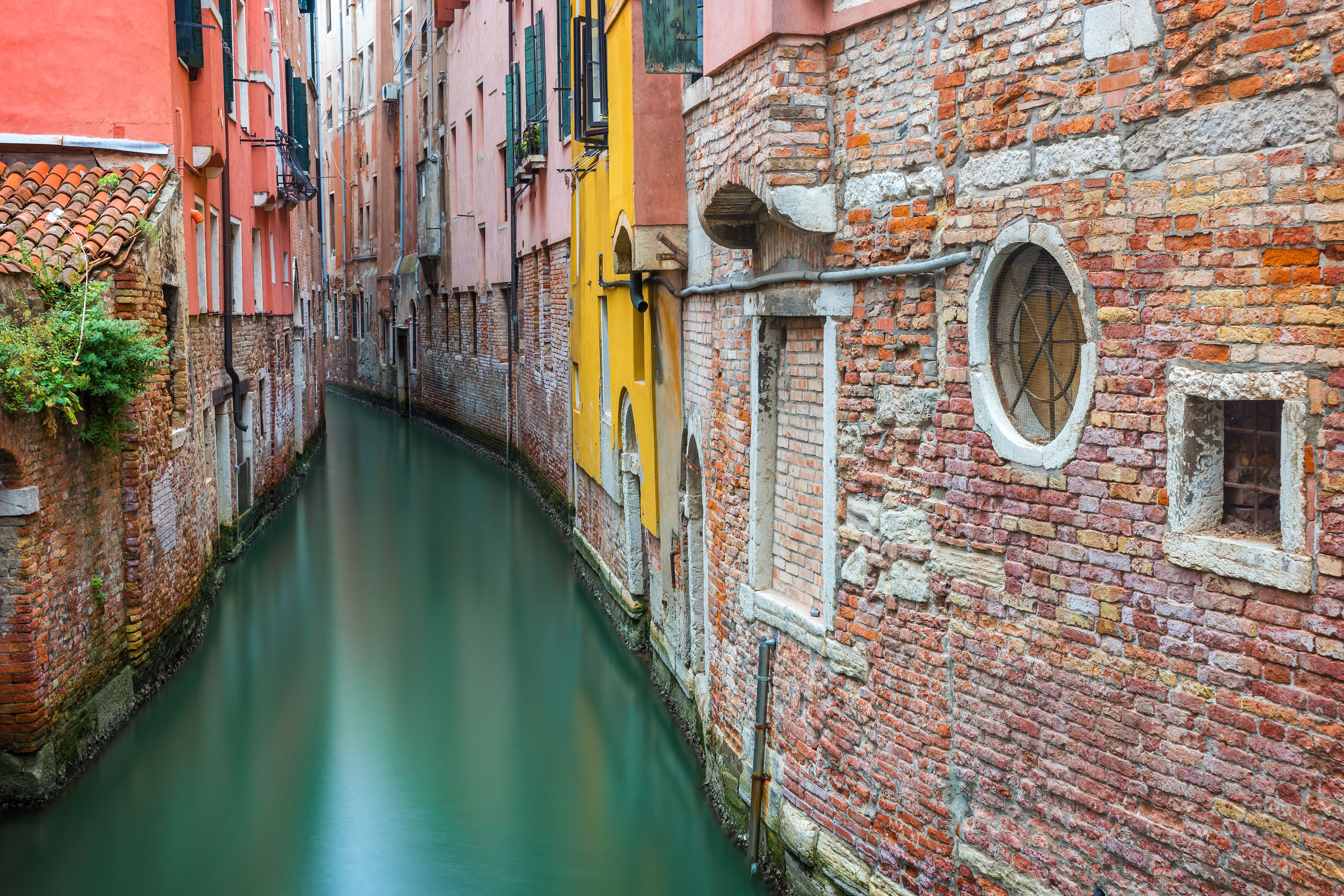 Serene canal flowing between colorful historic buildings in Venice, Italy.