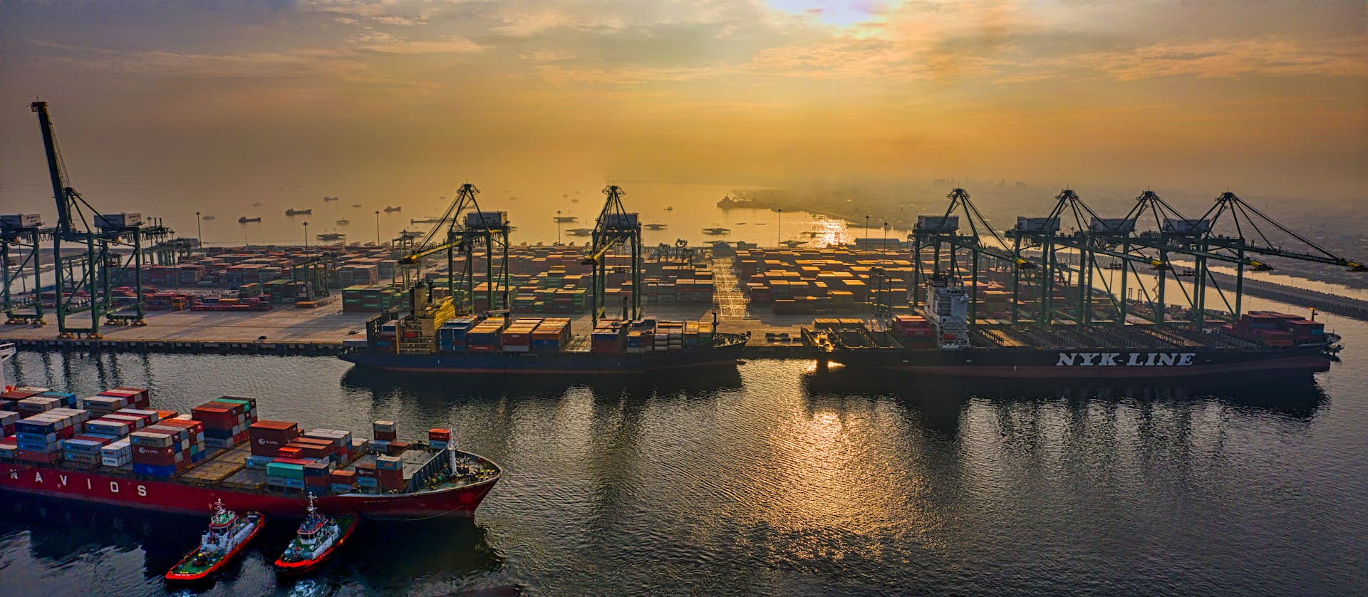 Dynamic aerial view of a bustling container port in Jakarta, Indonesia during sunset.