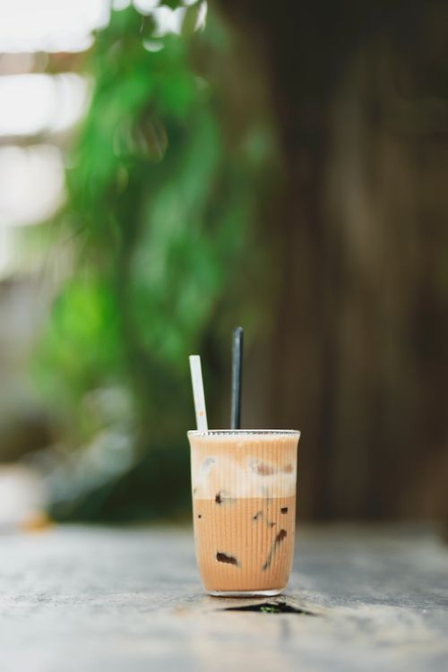 Free A delicious iced coffee in a clear cup with straws on a wooden table. Stock Photo