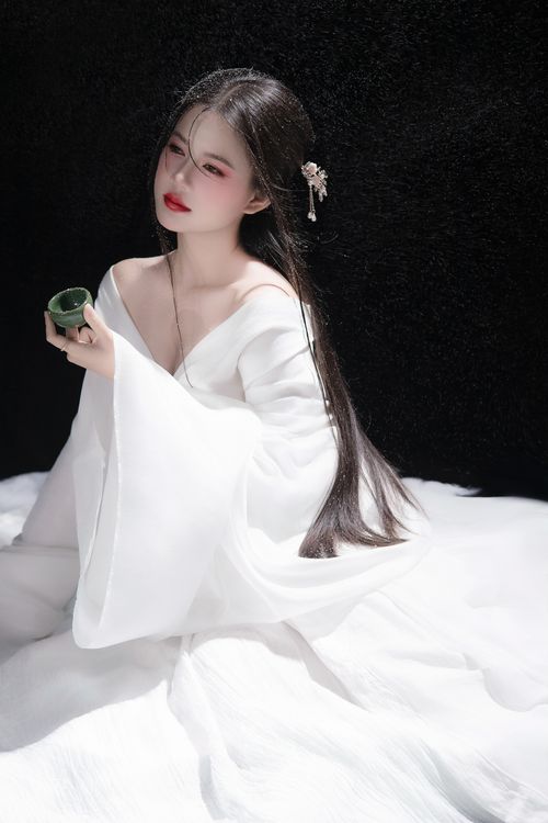 Free Elegant portrayal of a young woman in white traditional attire, holding a tea cup. Stock Photo